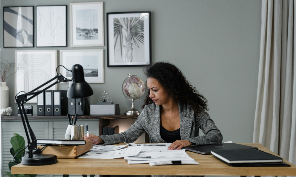 Mujer revisando documentos financieros en su escritorio, analizando informes y organizando la gestión de tesorería de la empresa.