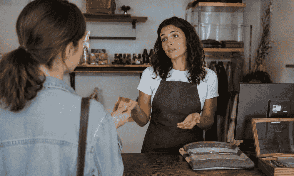 Comerciante explica a una clienta que su negocio no acepta pagos con tarjeta