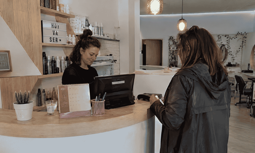 Cliente pagando con tarjeta en un centro de estética mediante un TPV de mostrador.