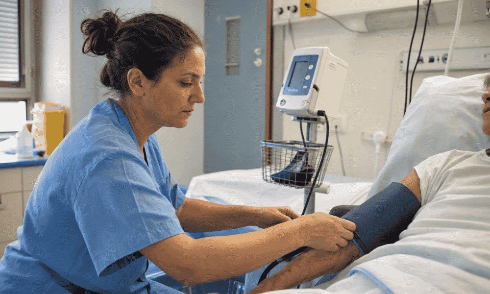 Enfermera del grupo de cotización 2 tomando la tensión arterial a un paciente hospitalizado.