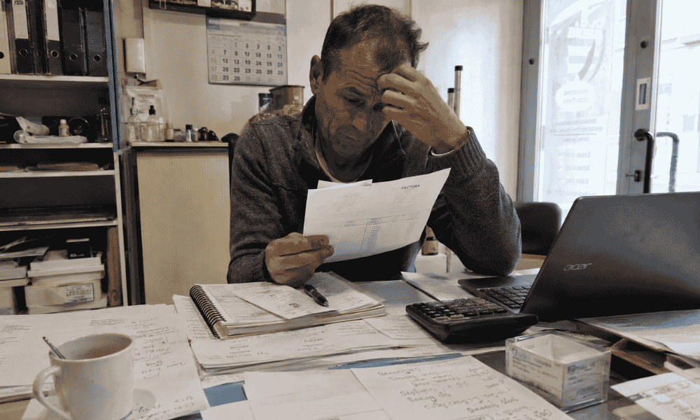 Empresario preocupado revisando facturas y cuentas debido a problemas de liquidez en su empresa.