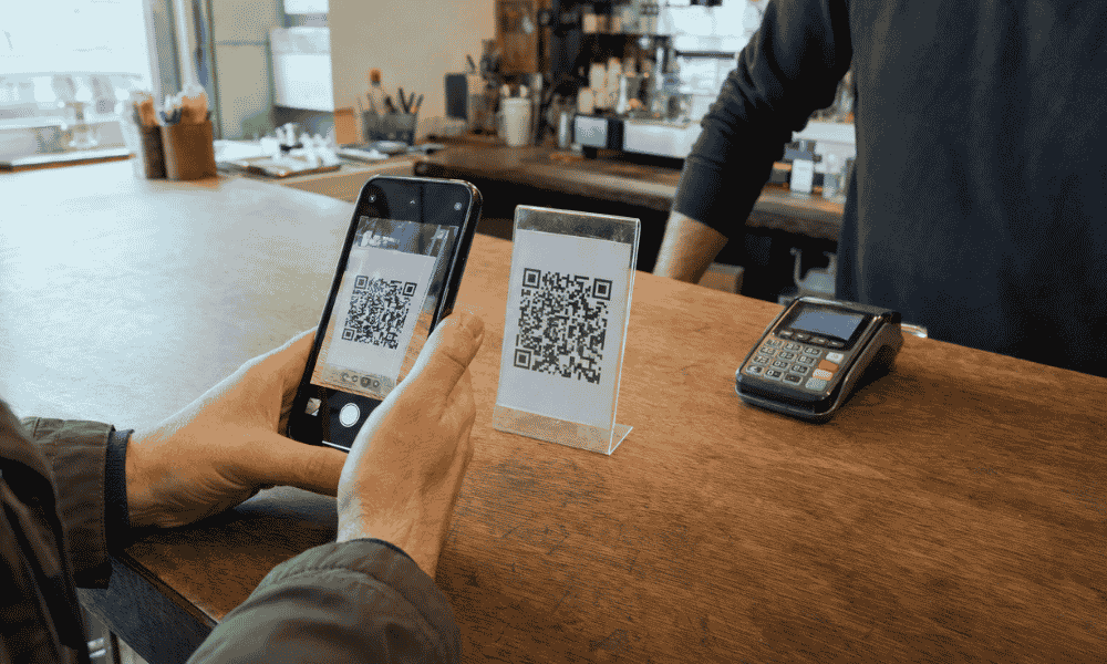 Cliente realizando un pago con código QR desde su teléfono móvil en un comercio físico.