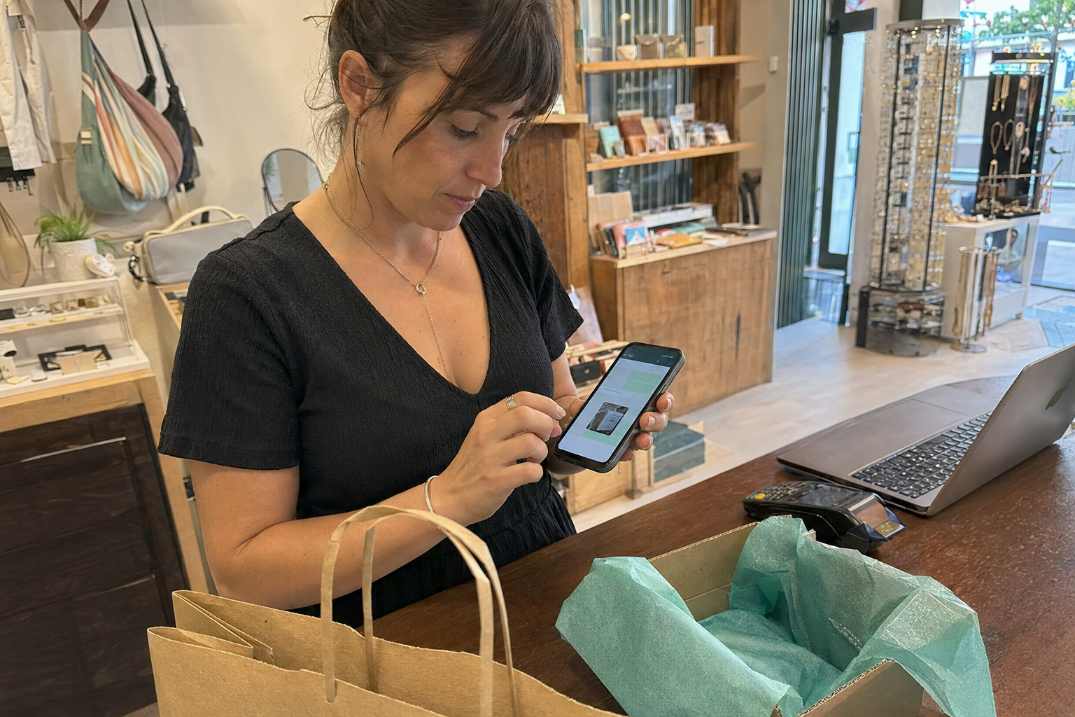 Comerciante enviando un enlace de pago desde su móvil a un cliente en una tienda.