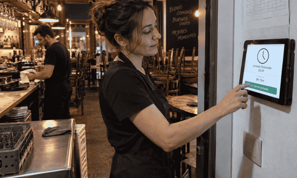 Trabajadora de hostelería registrando su salida mediante un sistema de fichaje digital obligatorio