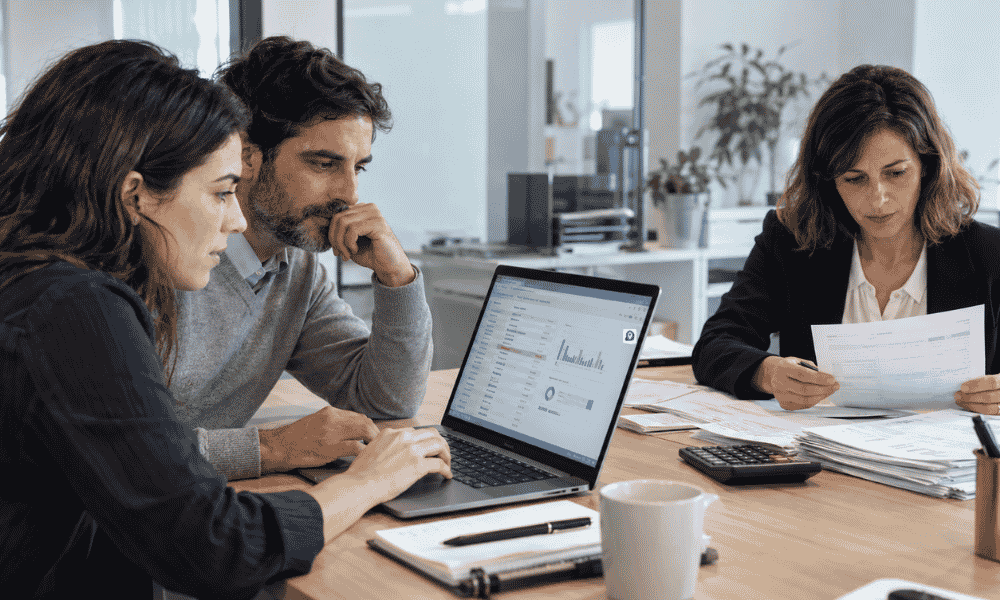 Equipo financiero revisando facturas y análisis asistidos por inteligencia artificial en una oficina.